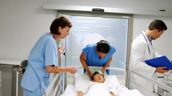 Doctors placing an oxygen mask and adjusting a iv drip to patient in emergency room