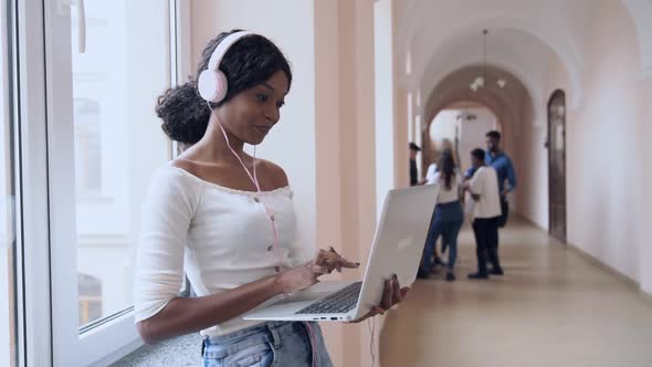 Beautiful Girl Standing in Hall with Laptop, Typing