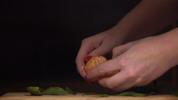 The girl divides the appetizing tangerine into slices.