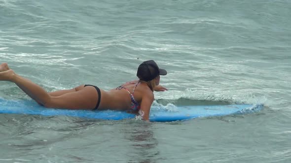 A young woman surfing in a bikini on a longboard surfboard.