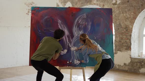 Passionate Couple Holding Smear Colorful Paints on Canvas Create Picture Together