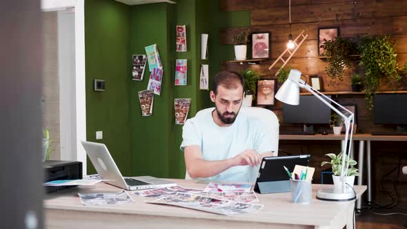 Creative Director Looking Into Her Tablet and Typing on His Laptop