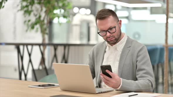 Creative Man Using Smartphone and Laptop