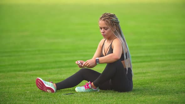 Girl with Phone Sitting on the Lawn