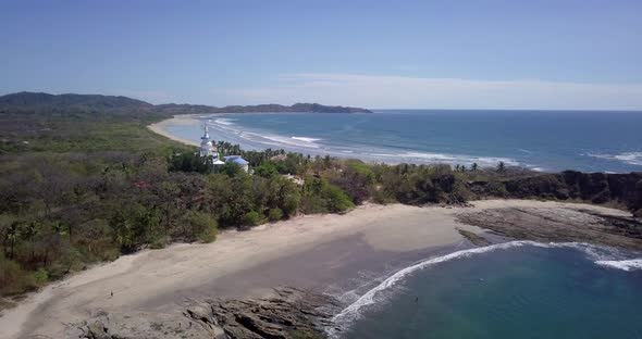 Aerial drone view of the beach, rocks and tide pools in Guiones, Nosara, Costa Rica.