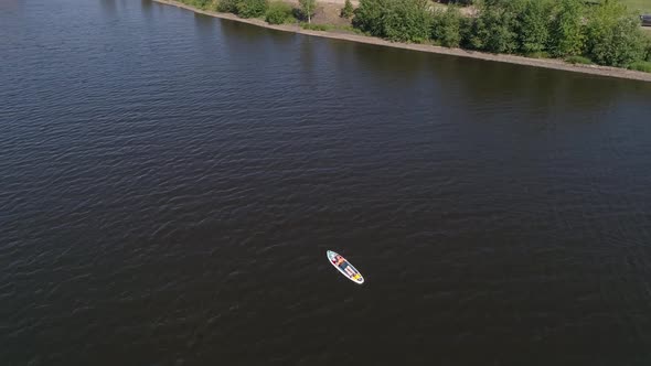 Aerial view of man lies on the paddle boarding (SUP) on pond 02
