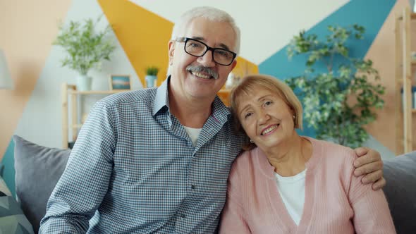 Portrait of Senior Man and Woman Couple Smiling and Laughing Sitting on Sofa at Home