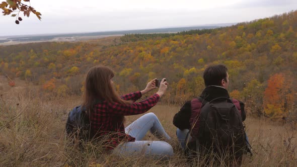 Free Travelers Man and Woman with Backpacks Make Selfie By Smartphone Hill. Tourists Are