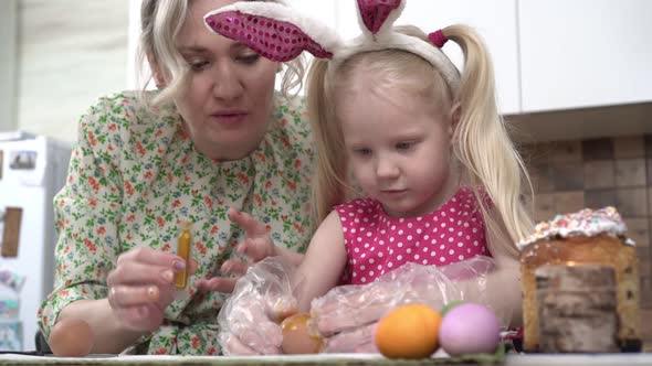 A Happy Family in the Kitchen Paints Eggs for the Christian Holiday of Easter