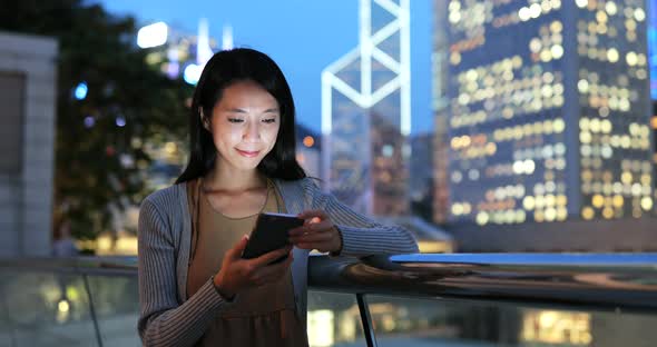 Woman looking at mobile phone in the city at night 
