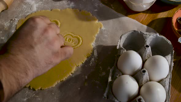 The man who prepares a special occasion cookie. Making cookies in dough with heart molds.