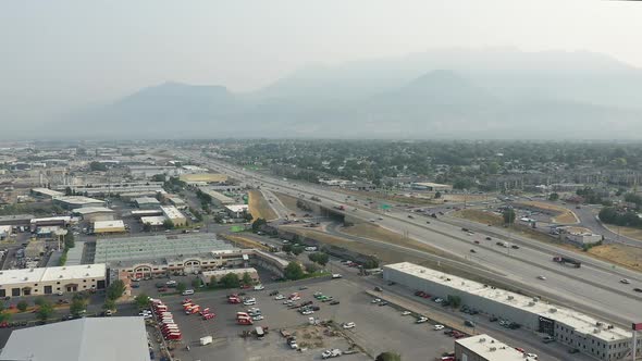 Aerial view rotating over industrial area next to freeway with smokey skies