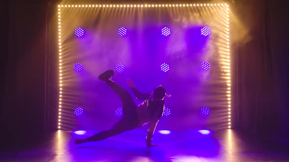 Break Dance Performed By a Young Guy in a Tracksuit. Silhouette of a Male Dancer Spinning on the