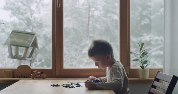 Side View of Kid Engineering Toy From Plastic Bricks Sitting By Window Home