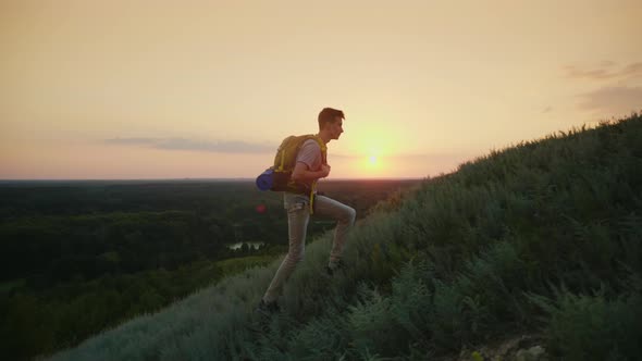 The Guy the Teenager with a Backpack Climbs Up the Mountain. At Sunset. Active Way of Life Since