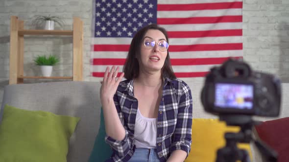 Young Woman Blogger in Shirt on American Flag Background Recording Video