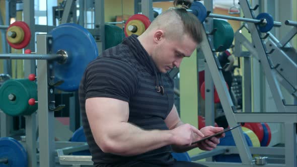 Athletic Man Using Digital Tablet in the Gym