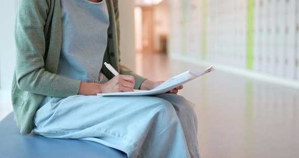 Woman writing on note at school