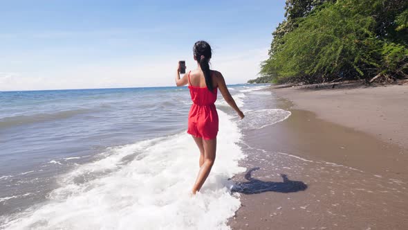 Travel Woman Vlogger Walking on the Beach and Recording Vlog on Smartphone