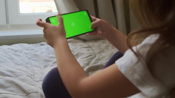 Child Holding a Smartphone with Green Monitor for Entertainment and Pastime