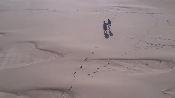 Drone Flying Over Couple Walking Along Dunes