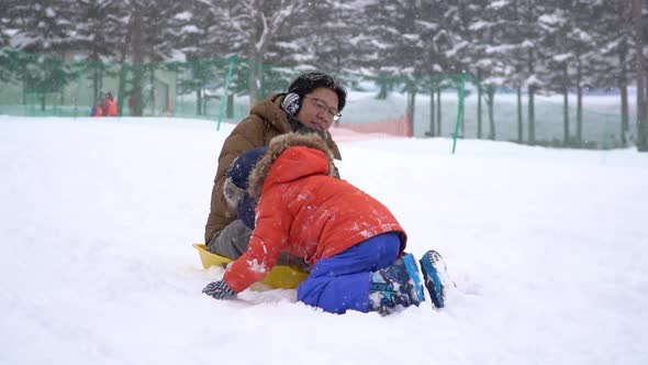 Asian Father And His Son Playing Sled Together