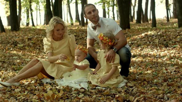 Mom, Dad and Children Having Fun in a Clearing in the Park Among the Fallen Maple Leafs