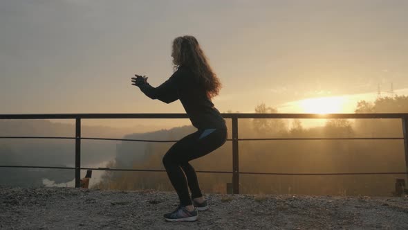 Young Muscular Fitness Woman Doing Squats Exercise in the Nature.