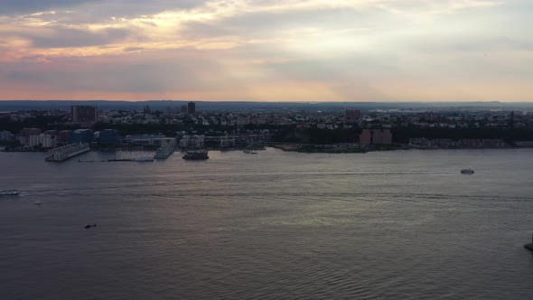 aerial shot of a helicopter landing, boats on the Hudson River in New York, during a golden sunset