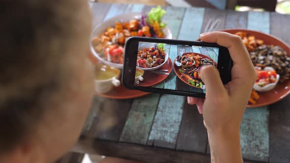 Female Food Blogger Taking Photo Of Healthy Food Using Smartphone In Restaurant