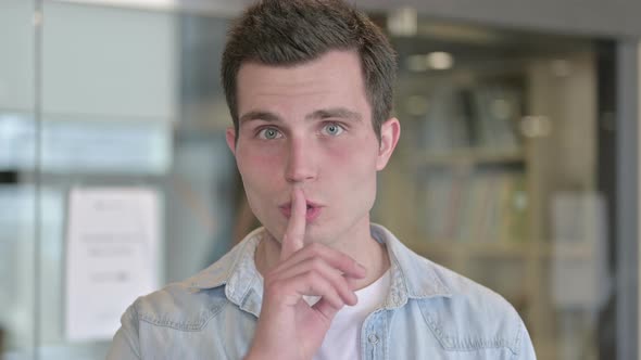 Portrait of Serious Young Male Designer Putting Finger on Lips