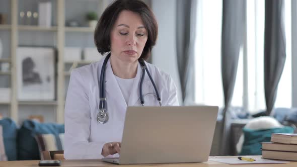 Old Lady Doctor Thinking While Working on Laptop