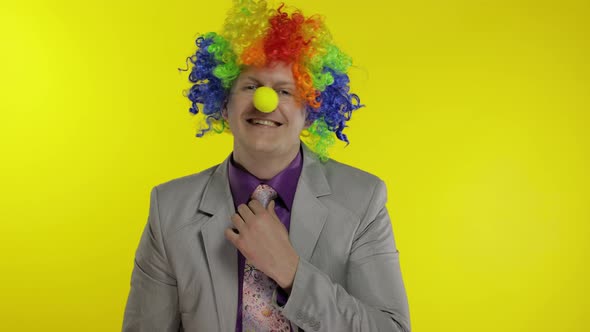 Clown Businessman Entrepreneur Boss in Wig Adjusts His Tie. Yellow Background