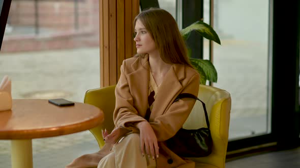 young Lonely sad woman looking away out of coffee shop window to city street