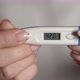 Woman Holds Thermometer in Hands to Measure Body Temperature - VideoHive Item for Sale