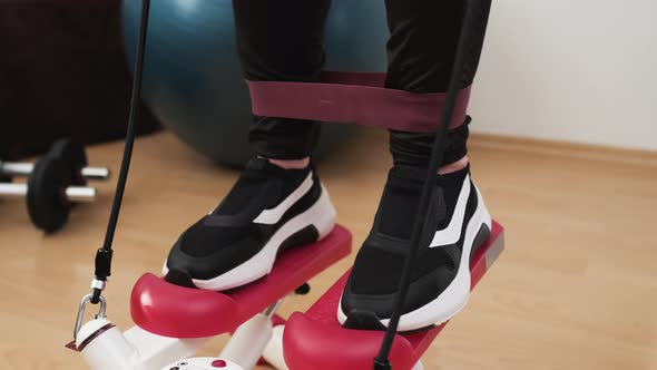 Close Woman Feet Doing Cardio on the Stepper and Using Elastic Bands with Ball and Dumbbells on the