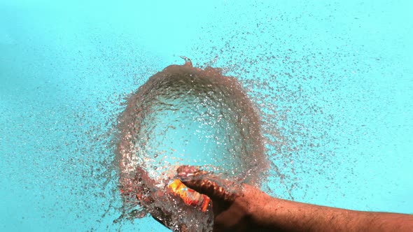 Orange Water Balloon Is Bursting In A Hand On A Blue Background In High Speed