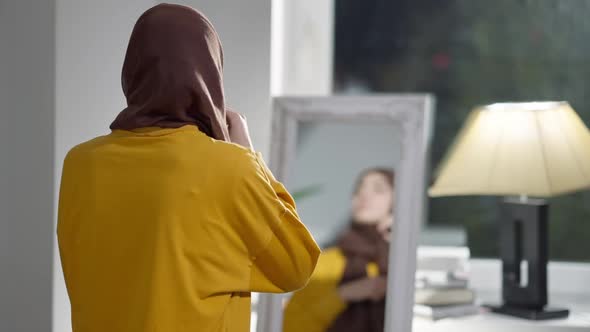 Back View of Slim Young Woman Adjusting Headscarf Turning to Camera Smiling