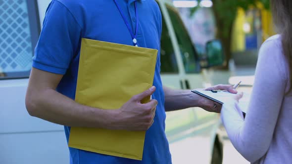 Woman Signing Proof Delivery Form and Receiving Yellow Package From Courier