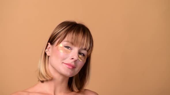 Beautiful Smiling Woman with Short Hair in Gold Eye Patches Looking in Camera and Smiling Over