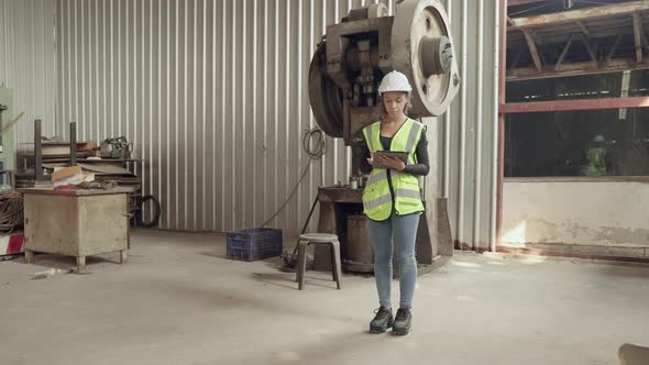 African American female worker examines and inspects the equipment inside the factory