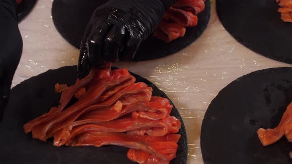 Palm Hands in Black Gloves Put Delicious Sliced Salmon Fish on Stone Plates Range Pieces of Fish