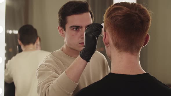 A Man Eyebrow Master Working with Brows of His Male Client  View From the Mirror