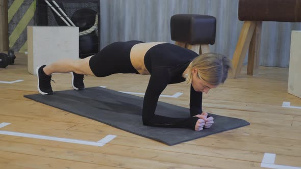 Young athletic pretty woman doing plank the gym. Concept of sport and healthy lifestyle