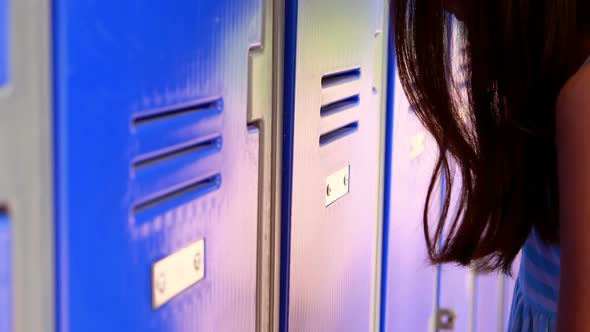 Sad schoolgirl leaning on lockers 4k