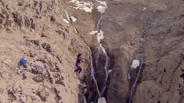 A man balances while tightrope walking and slacklining across a canyon