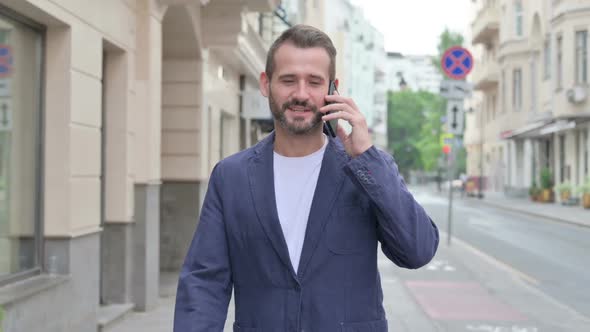 Man Attending Phone Call While Walking on Beautiful Street