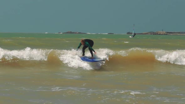 Beginner surfer girl falling off surfboard into waves, Morocco, Essaoiura