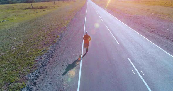 Low Altitude Flight in Front of Sporty Man at Perfect Asphalt Road