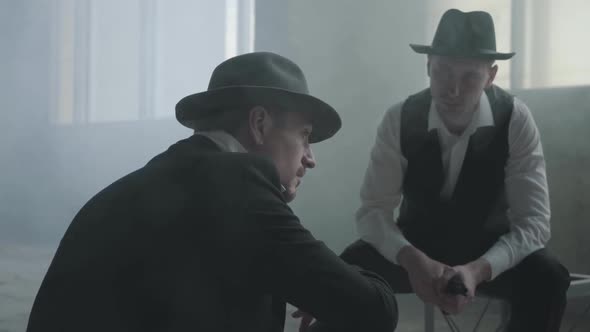 Portrait Two Stylish Men in Hats Sitting in an Abandoned Building Discussing Business